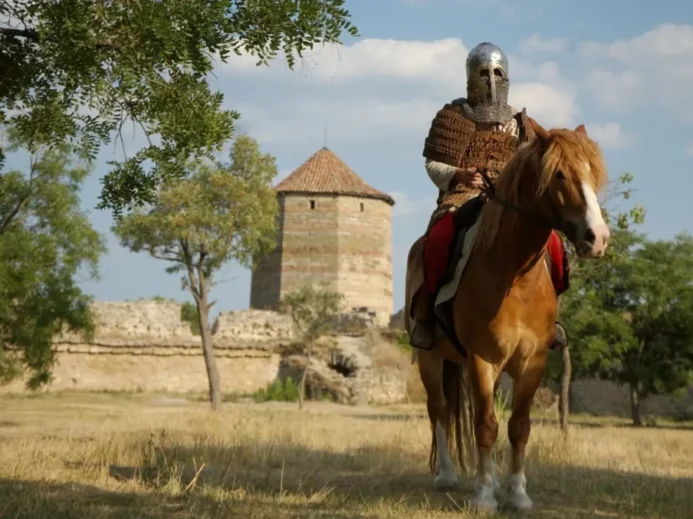 Středověký rytíř na koni u staré kamenné věže